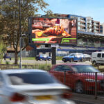 Digital roadside billboard on Butts Road in Coventry displaying DOOH advertising to passing traffic.
